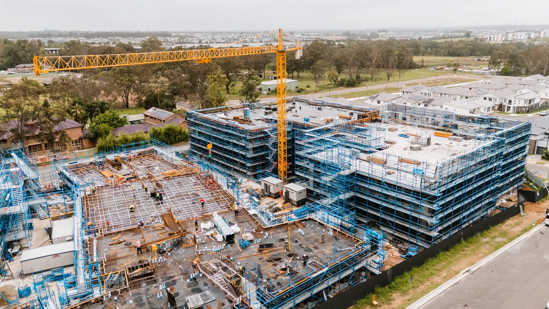 Aerial view of an apartment development under construction with deck formwork and tower cranes